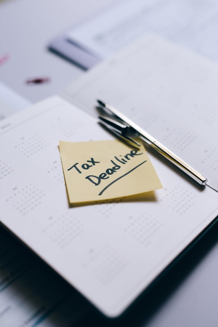 Sticky note on calendar highlighting tax deadline with pen nearby.